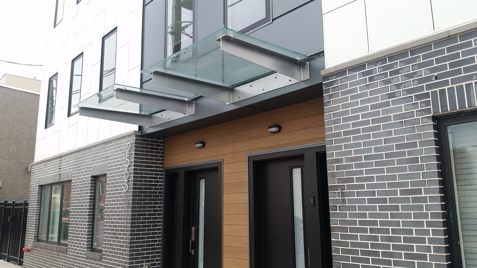 Commercial building entrance with glass canopies and dark-framed entry doors.